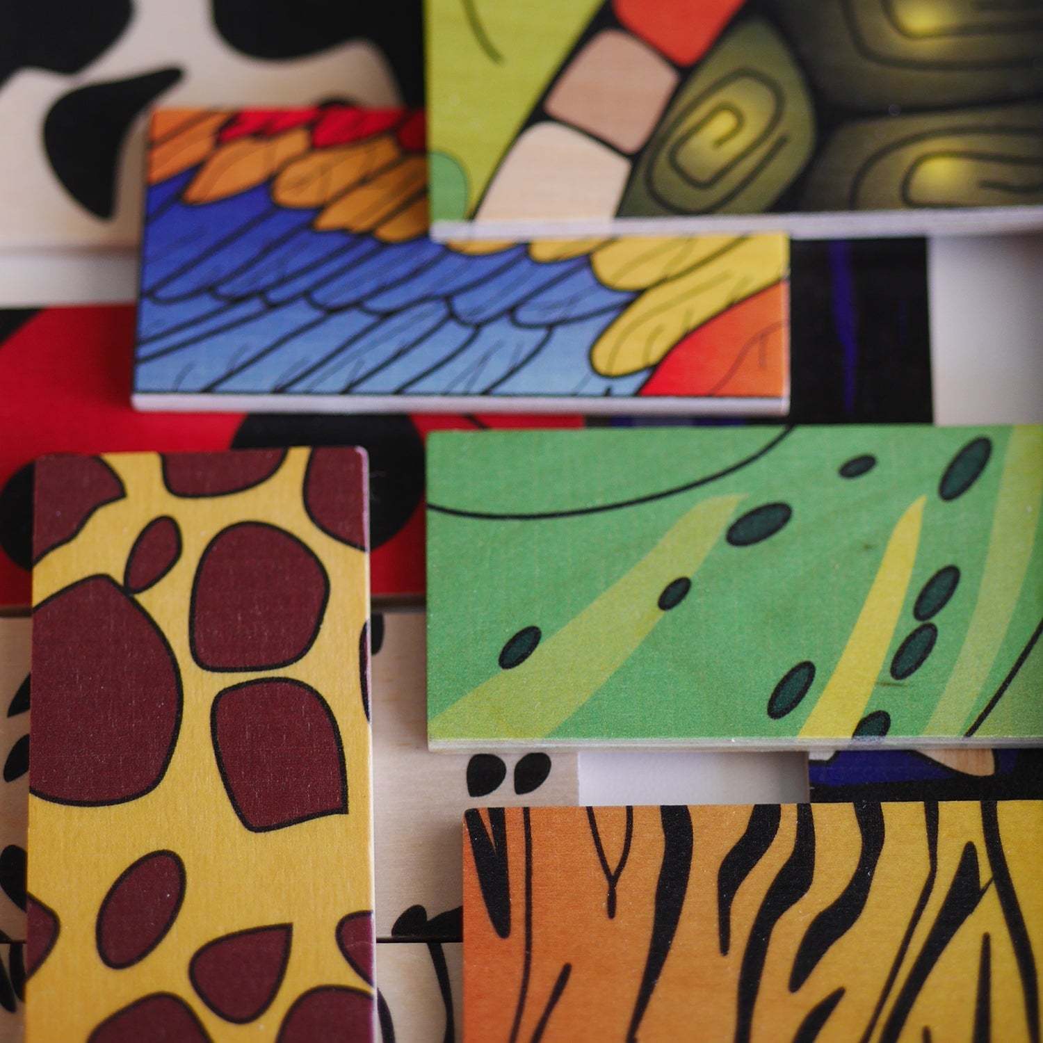 Wooden matching tiles featuring colorful animal skin patterns like giraffe, tiger, and bird feathers for educational play.