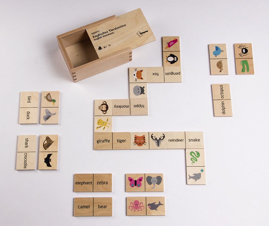 Wooden animal dominoes with colorful illustrations and text labels, arranged on a white surface with a matching storage box.