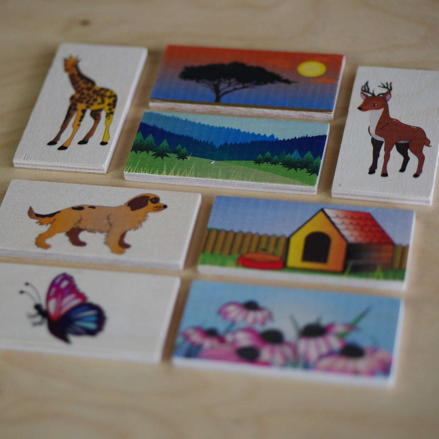 Wooden matching tiles featuring colorful illustrations of animals and their natural habitats for educational play.