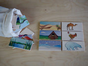 Wooden animal habitat matching tiles with illustrated pairs and a storage bag on a light wood surface.