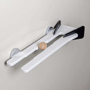 White wall-mounted shelf with black accents and a small wooden ball resting in the center track.