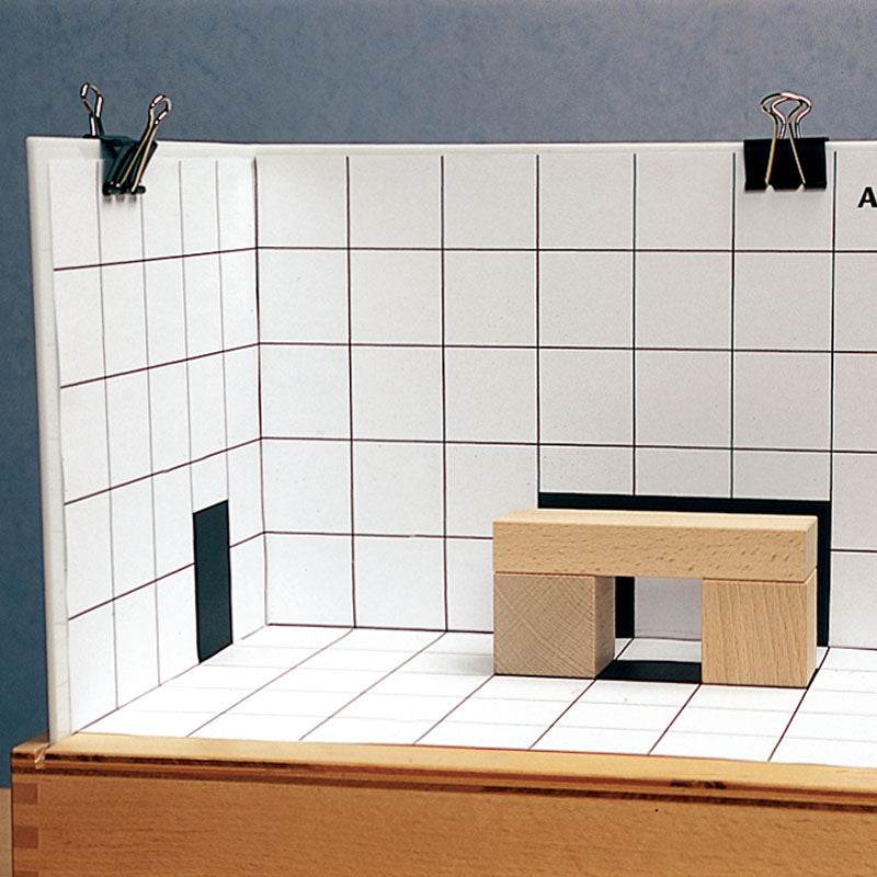 Wooden blocks arranged on a white grid board to match black shadow silhouettes in a Big Shadows puzzle set.