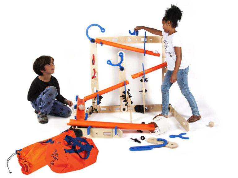 Children building a large wooden and orange plastic marble run set with modular tracks and connectors.