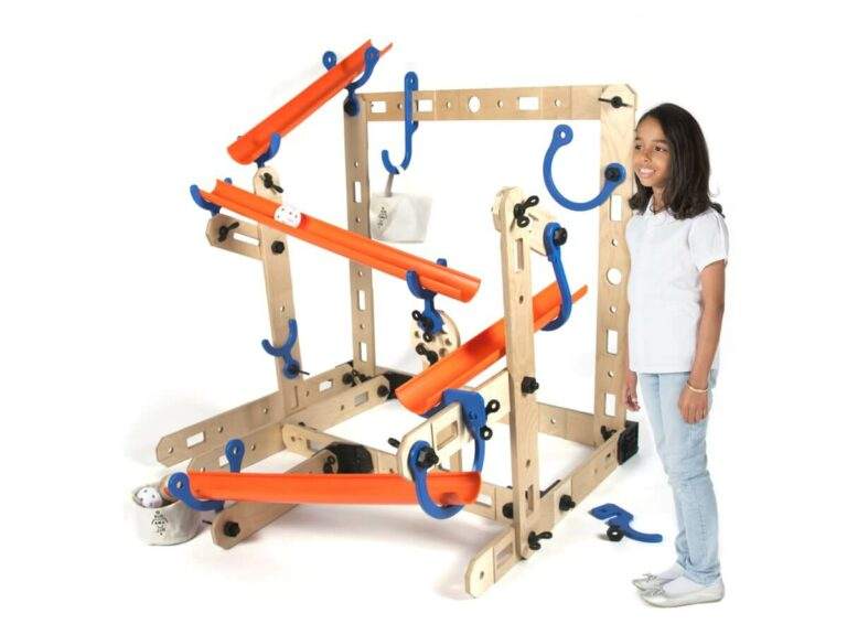 Large wooden modular marble run set with orange tracks and blue connectors, standing next to a young girl.