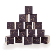 Pyramid of dark wooden blocks featuring debossed gold constellation patterns and star maps on a white background.
