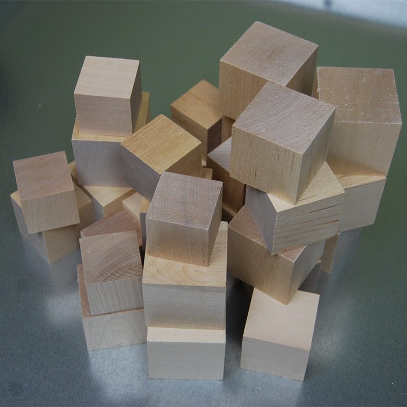 A collection of natural, unfinished wooden cubes in varying sizes for open-ended STEM play and building.