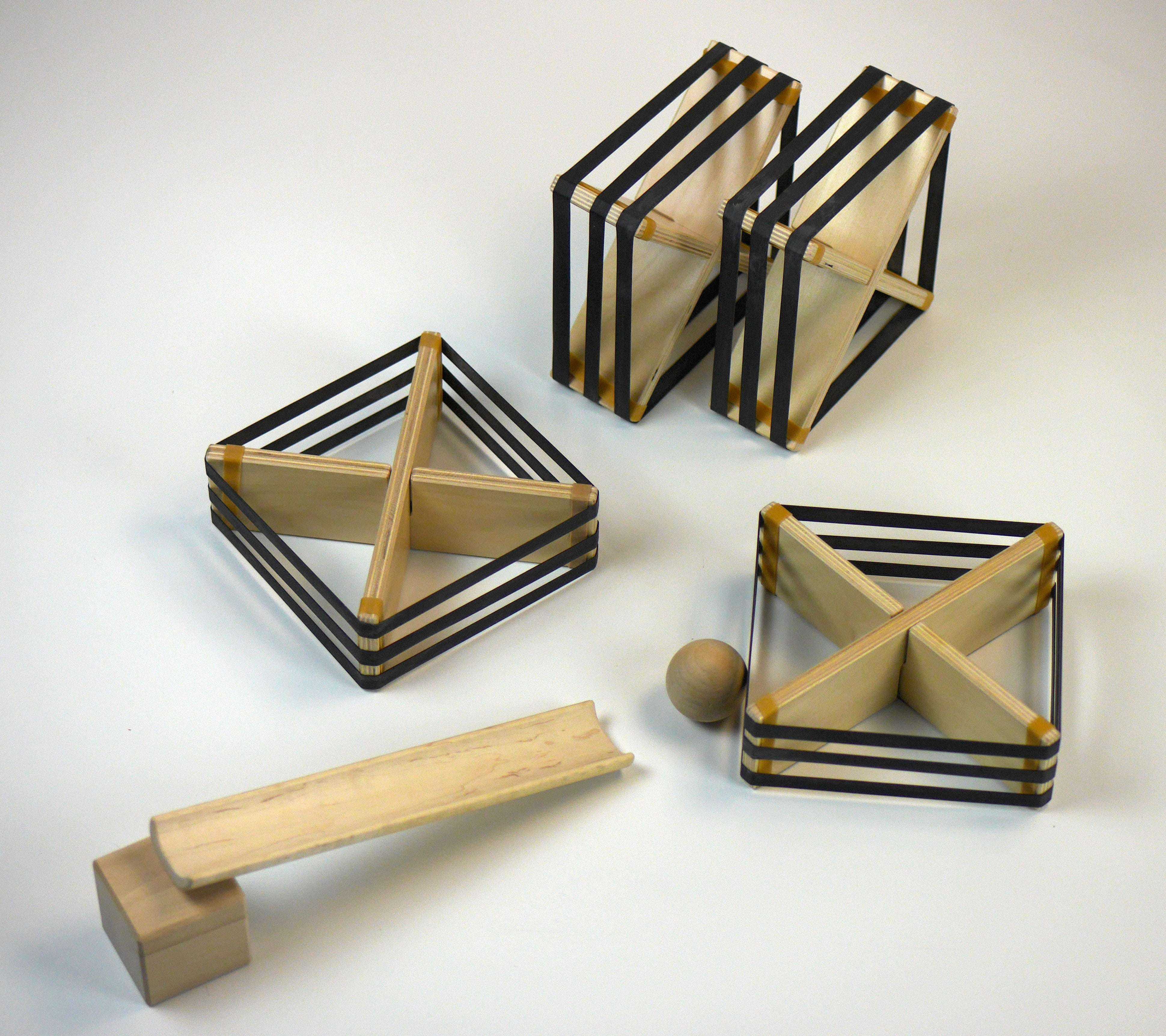 Wooden geometric deflector set with black elastic bands, a small wooden ball, and a ramp piece on a white background.
