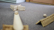 Natural wood deflector set pieces arranged on a gray carpet with wooden balls for geometry and ramp play.