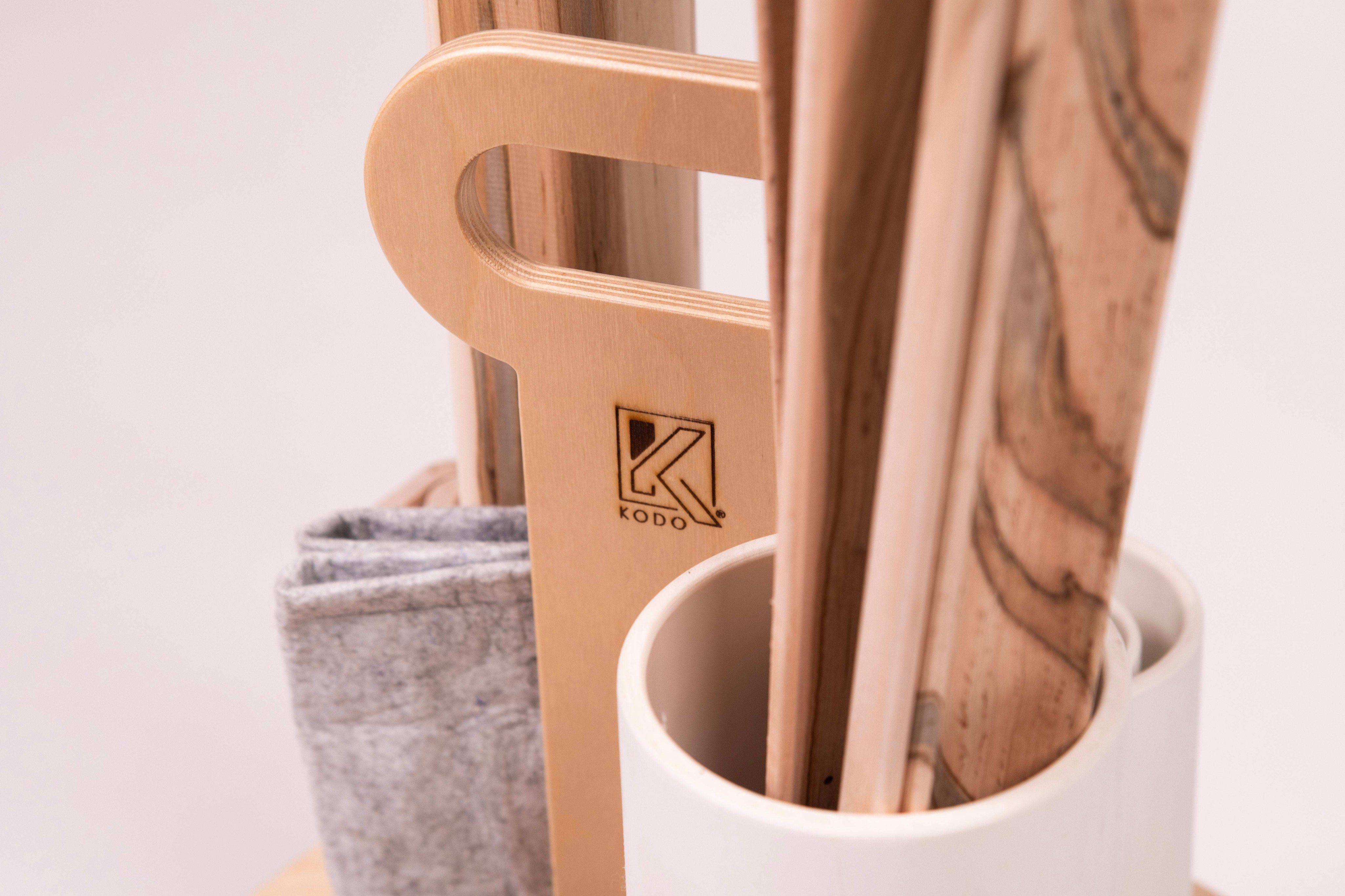 Wooden Kodo ramp caddy with storage tubes, natural wood grain ramps, and a grey canvas pouch on a white background.