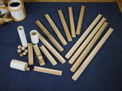 Hand-finished wooden ramps, white tubes, and small wooden balls for a STEM building set arranged on a blue mat.