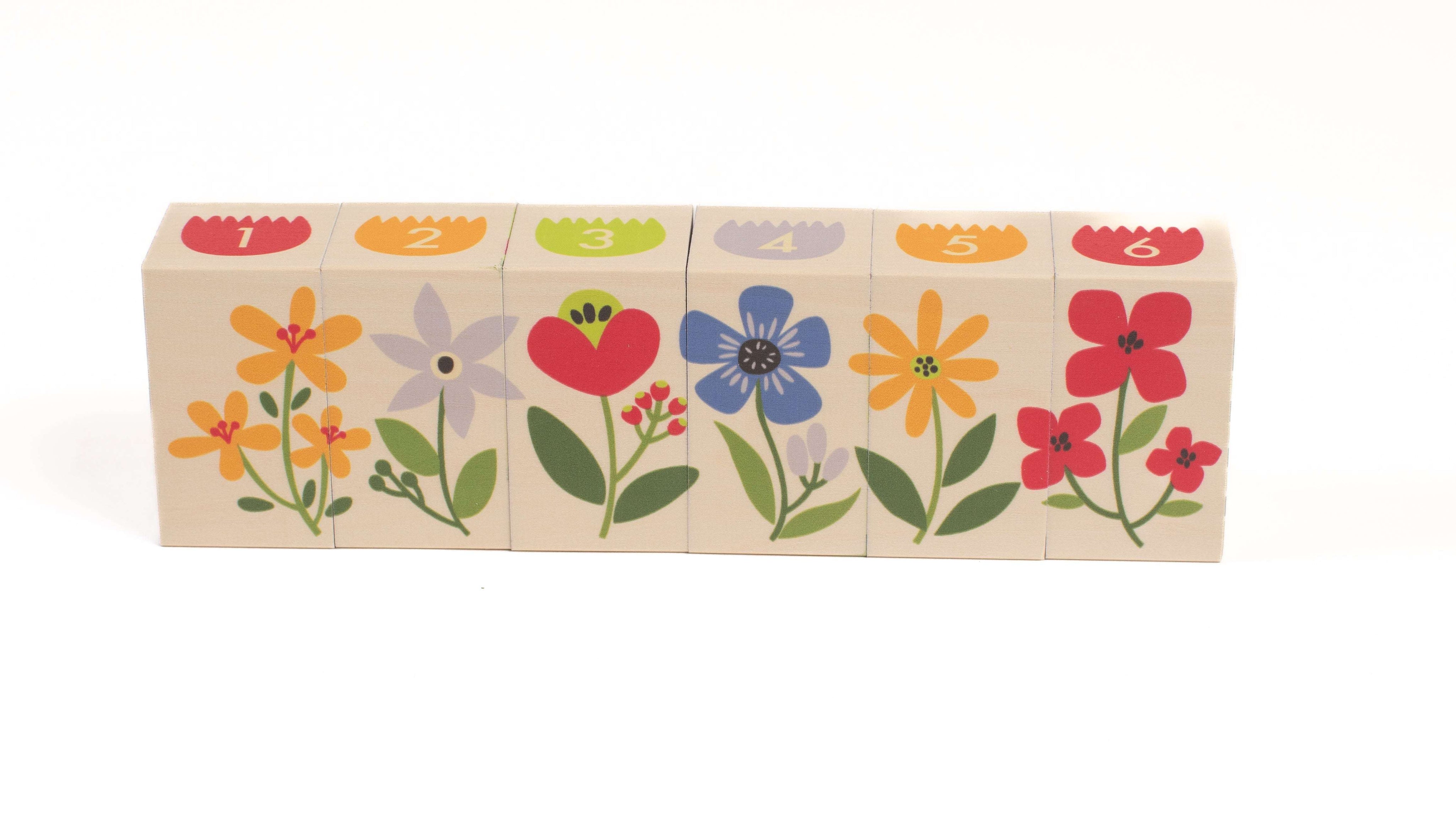 Six wooden blocks featuring colorful garden flowers and numbered tops in a row.