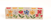 Six wooden blocks featuring colorful garden flowers and numbered tops in a row.