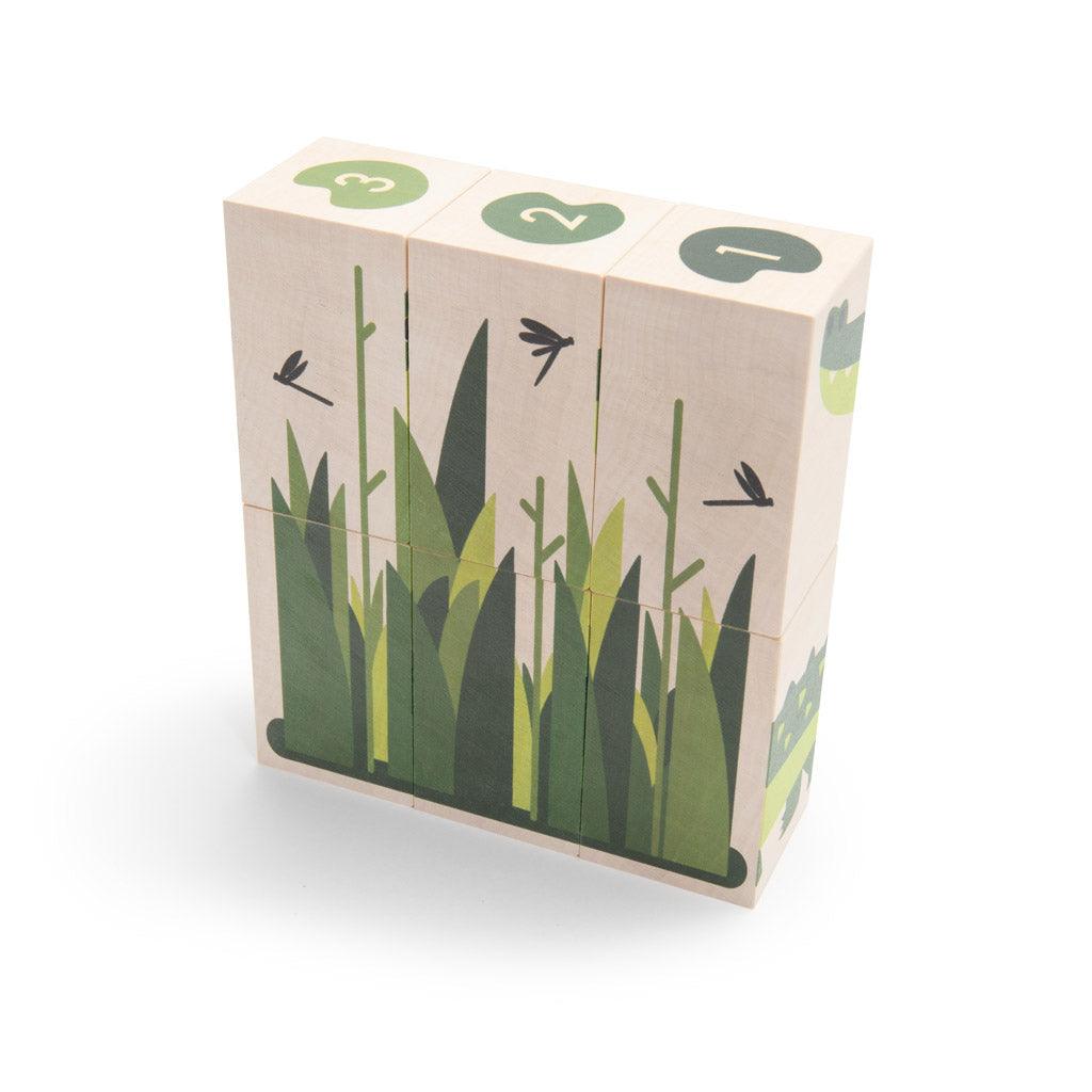 Six sustainable basswood blocks featuring swamp illustrations, green grass, and numbered lily pads on a white background.