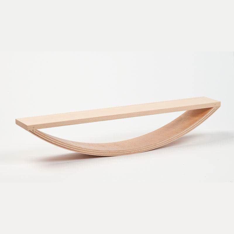 Experimental seesaw made of light-colored beech multiplex wood with a curved base for balancing blocks and toys.