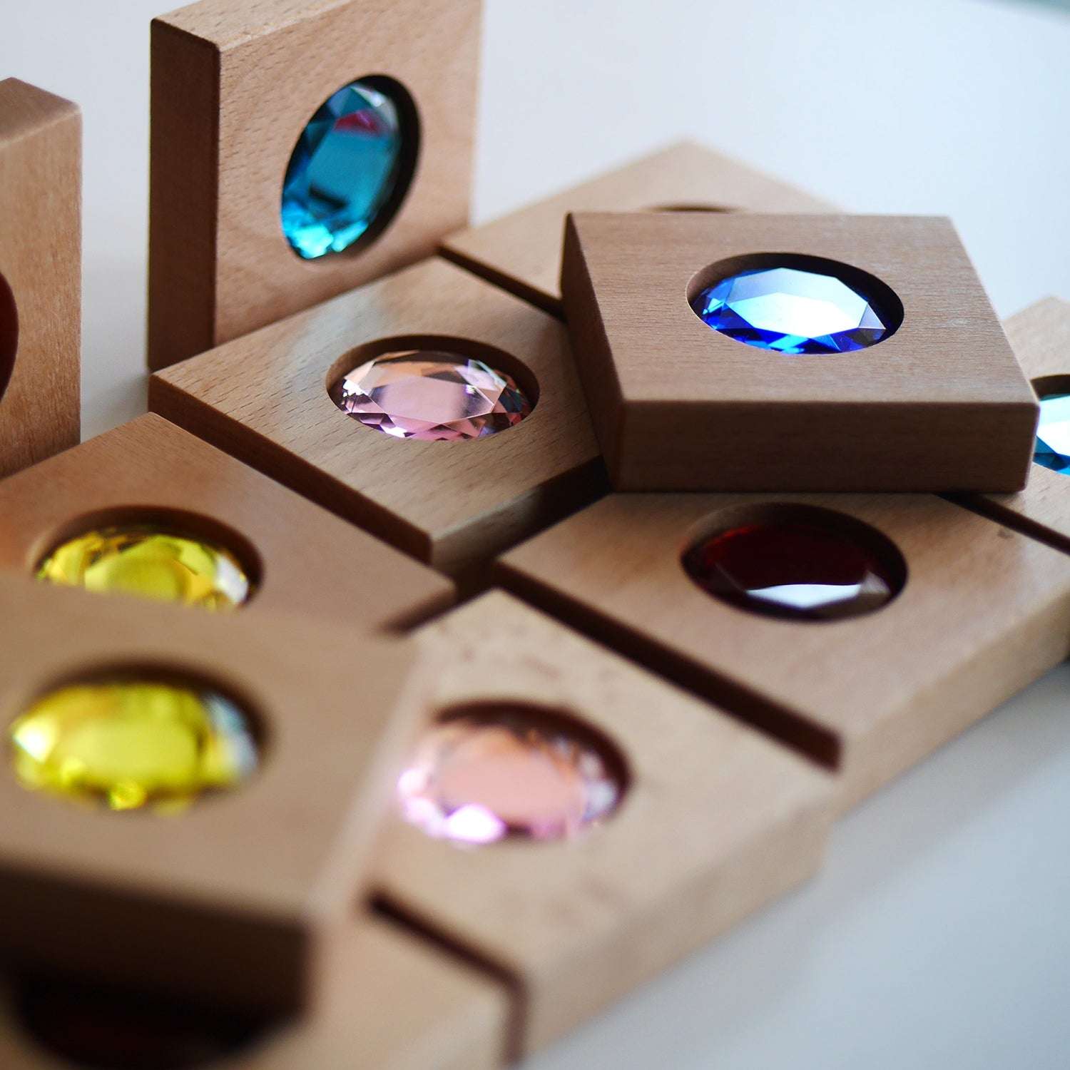 Chunky wooden tiles with vibrant, faceted colorful gemstones for sensory play and color matching activities.