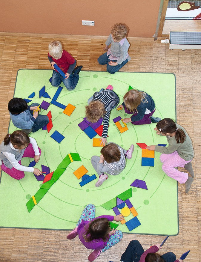 Children creating colorful designs with giant pattern tiles and geometric shapes