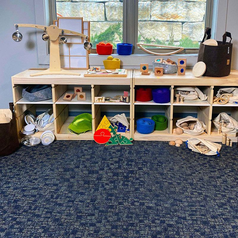 Wooden shelving unit filled with colorful STEM learning materials, loose parts, and an experimental seesaw for early childhood.