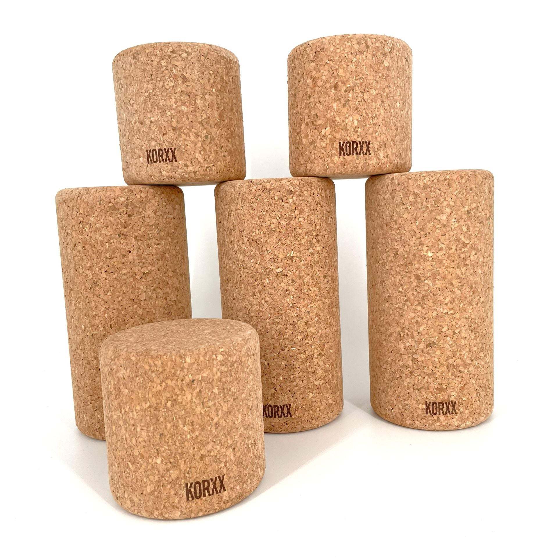 Set of five cylindrical KORXX natural cork building blocks in varying heights on a white background.