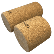 Two cylindrical KORXX cork building blocks with a natural tan textured finish on a white background.