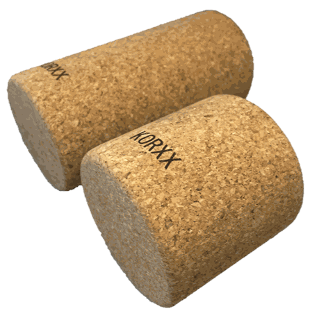 Two cylindrical KORXX cork building blocks with a natural tan textured finish on a white background.