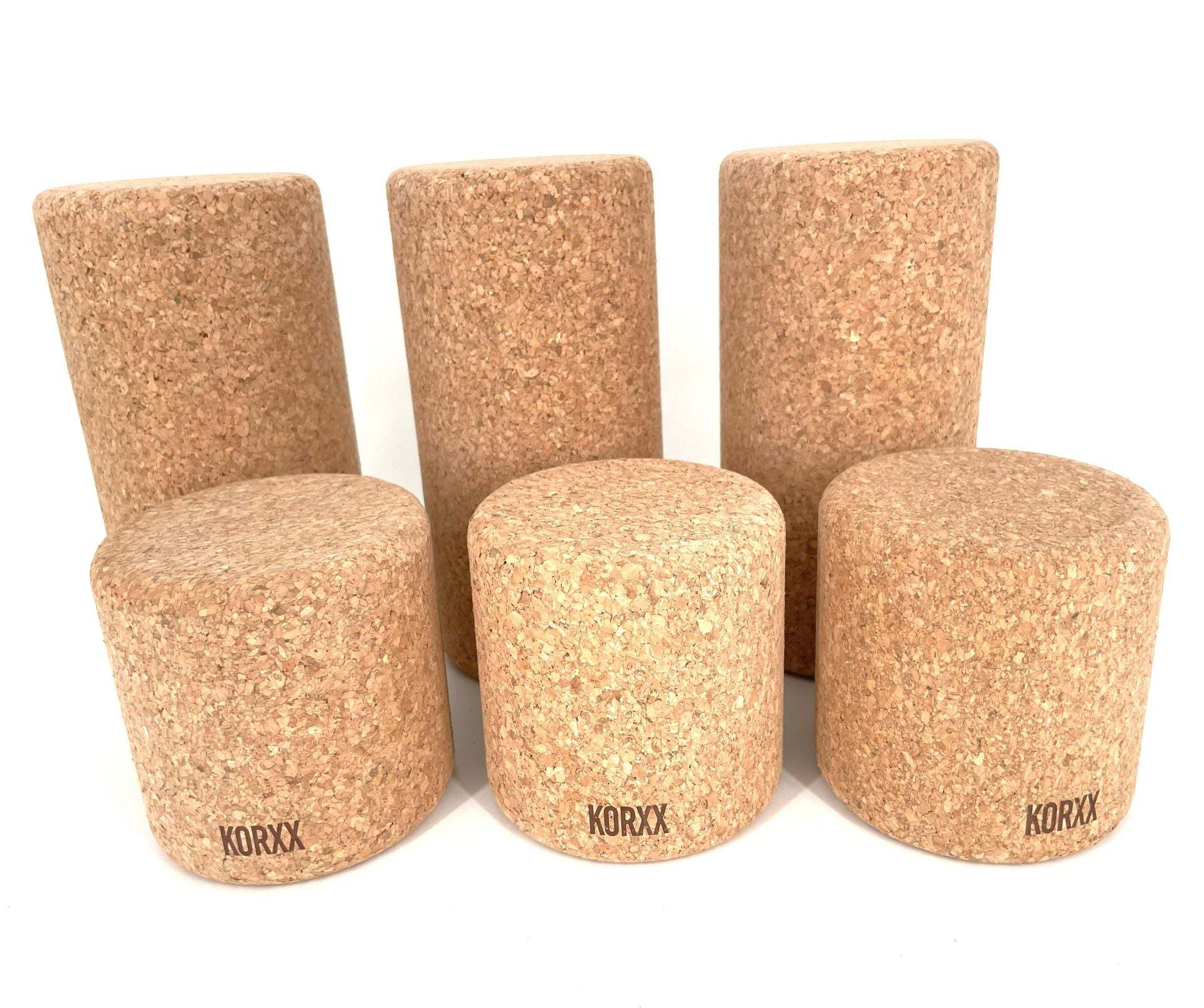 Set of six cylindrical Korxx cork building blocks in varying heights with a natural tan textured finish.