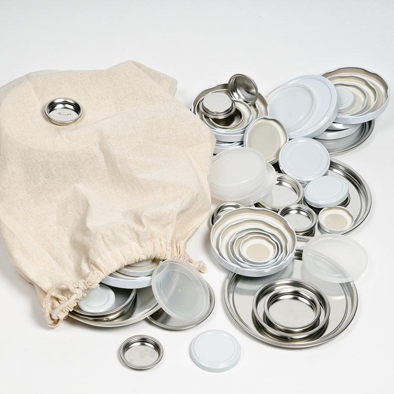 Set of 85 assorted metal and plastic lids in various sizes and white tones, displayed with a natural cotton storage bag.