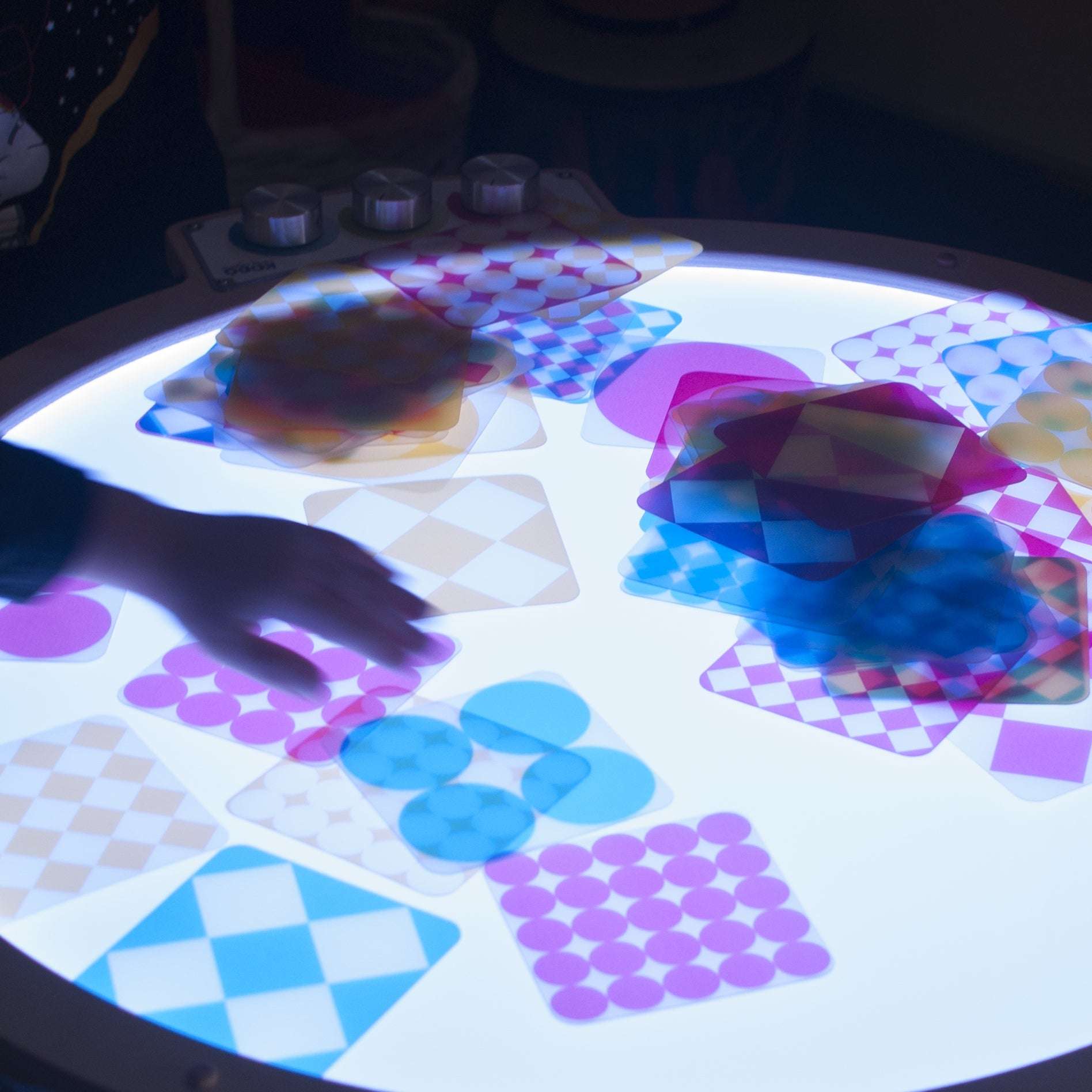 Child using Light Lab Panel with red, green, and blue knobs to mix light colors in classroom setting