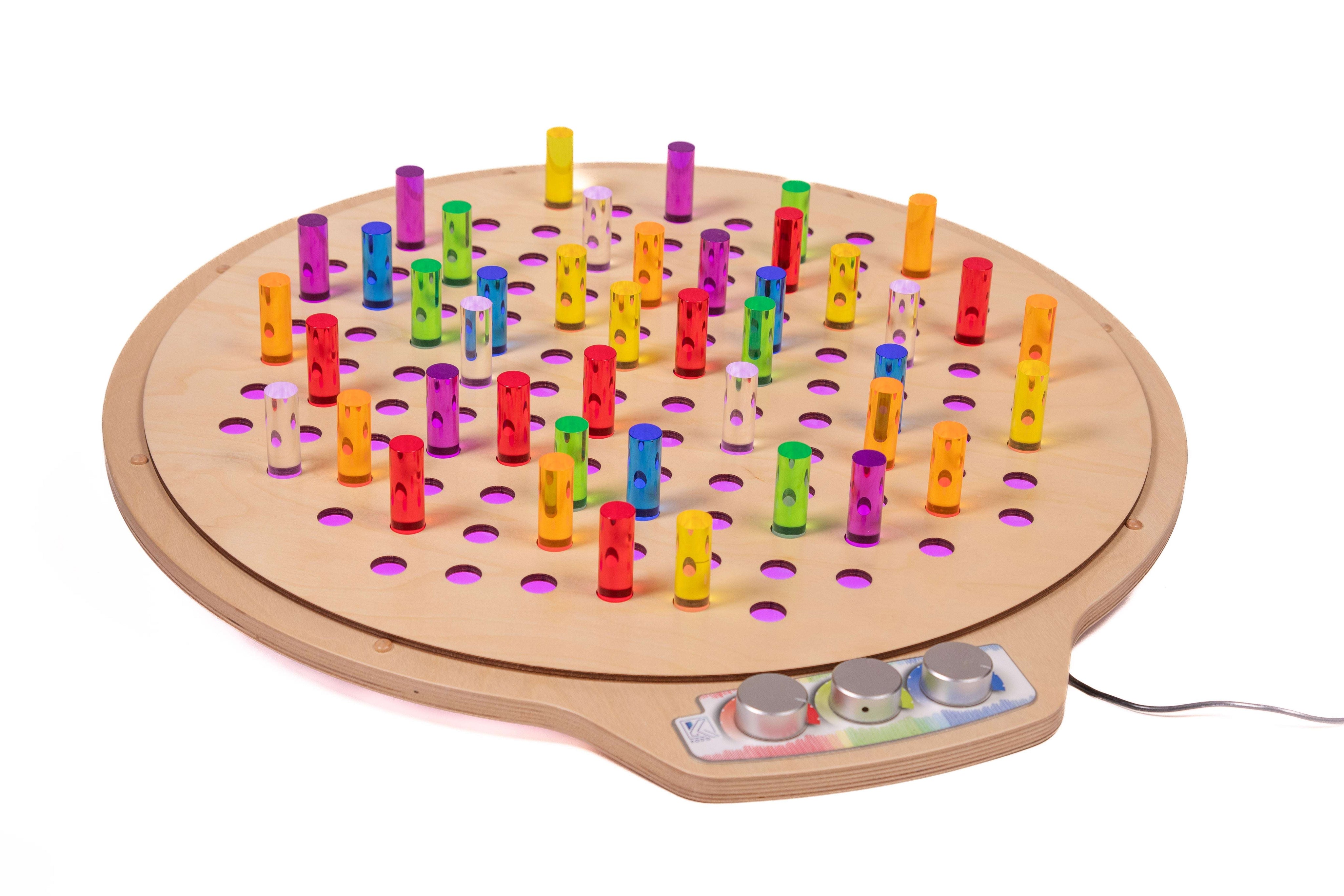 Circular birch pegboard with colorful translucent acrylic pegs and light control knobs on a white background.