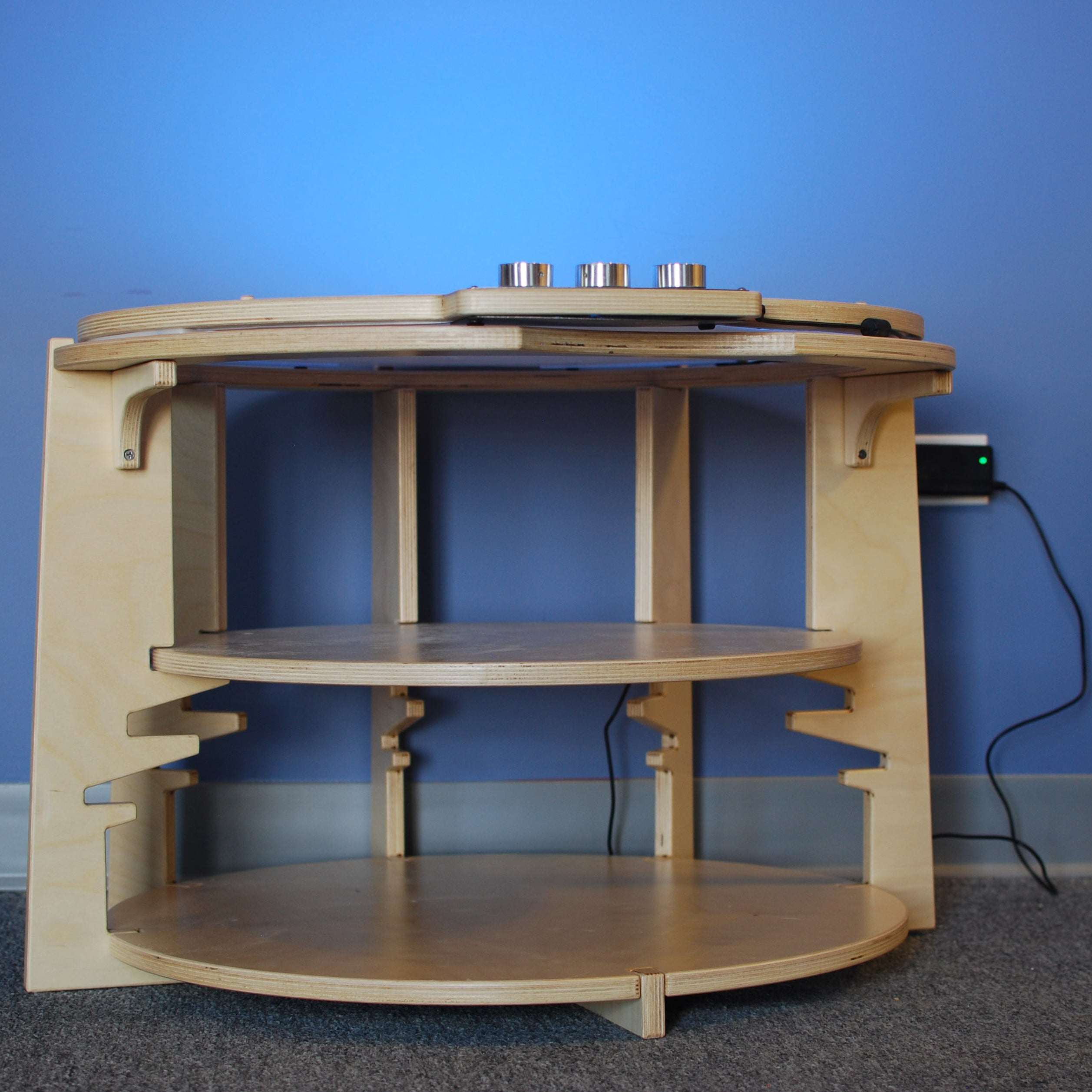 Light-colored plywood storage pod featuring two circular shelves and dedicated slots for light lab accessories.