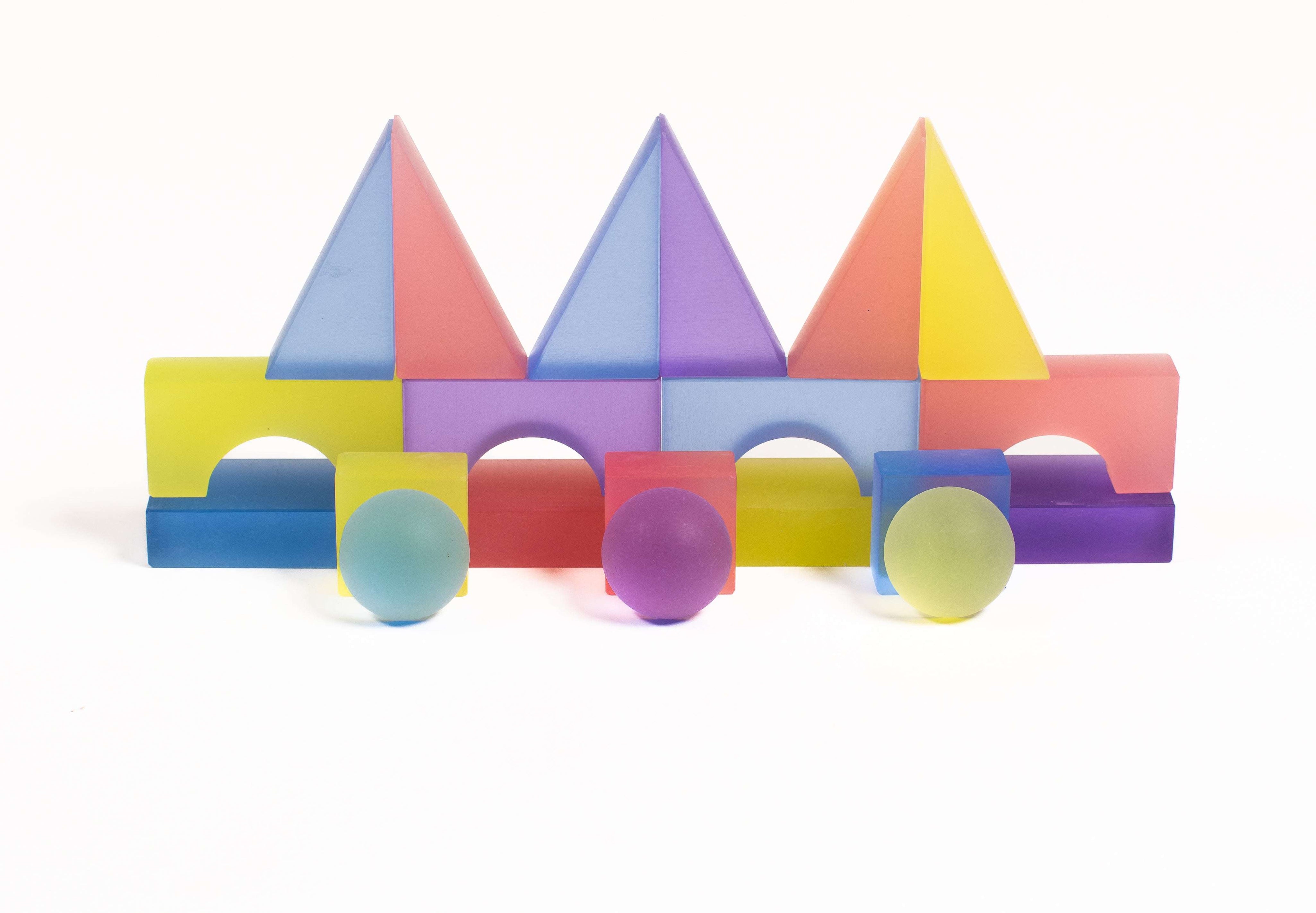 Colorful frosted translucent building blocks in geometric shapes arranged on a white background.