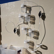 Modular water circuit with clear cups, tubing, and black hand pumps mounted on a magnetic wall for STEM play.