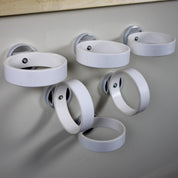 Five white circular magnetic rings attached to a wall for educational play and physics experiments.