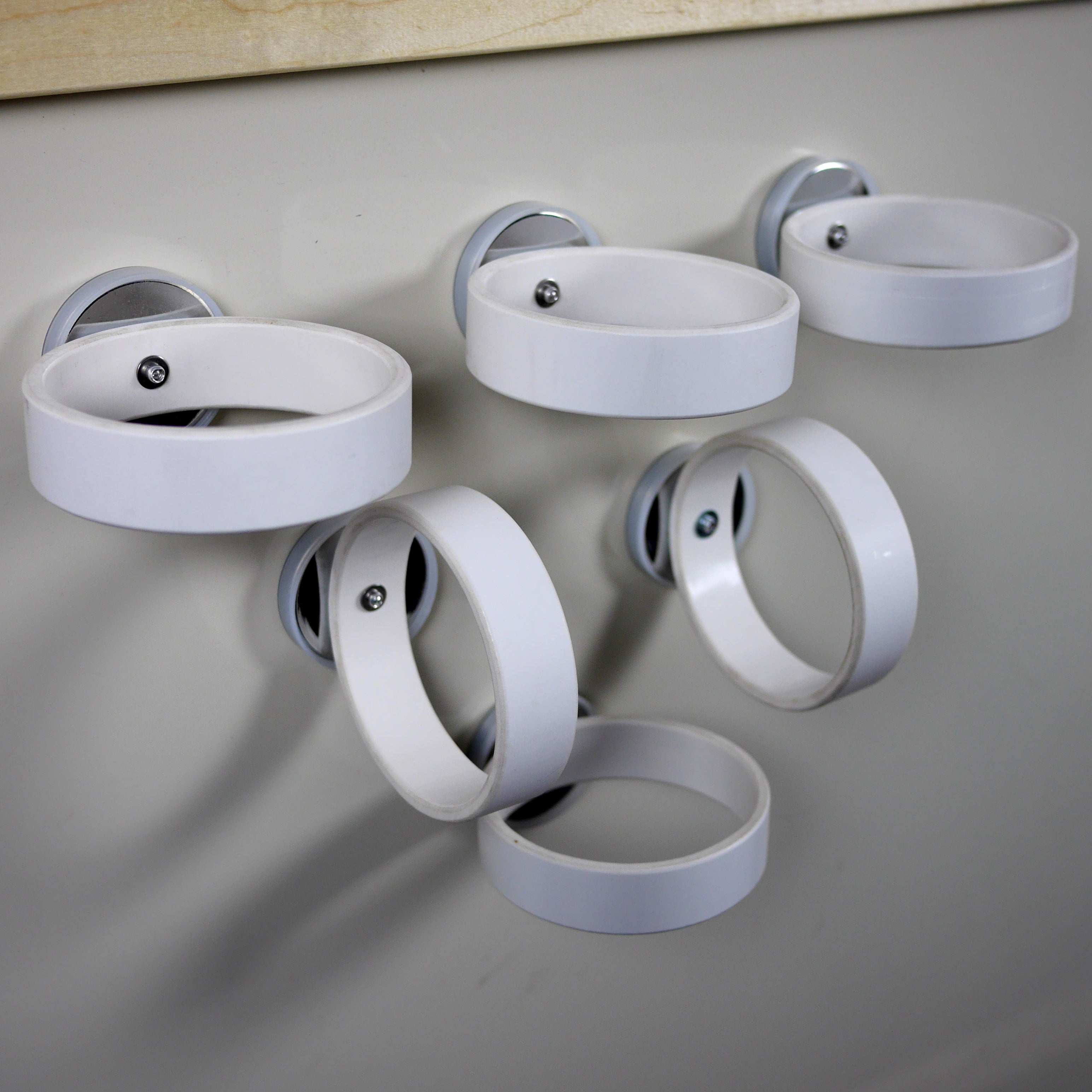 Five white circular magnetic rings attached to a wall for educational play and physics experiments.