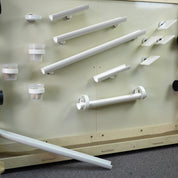 White magnetic gutters, ramps, and cups arranged on a light-colored wall for interactive STEM play.