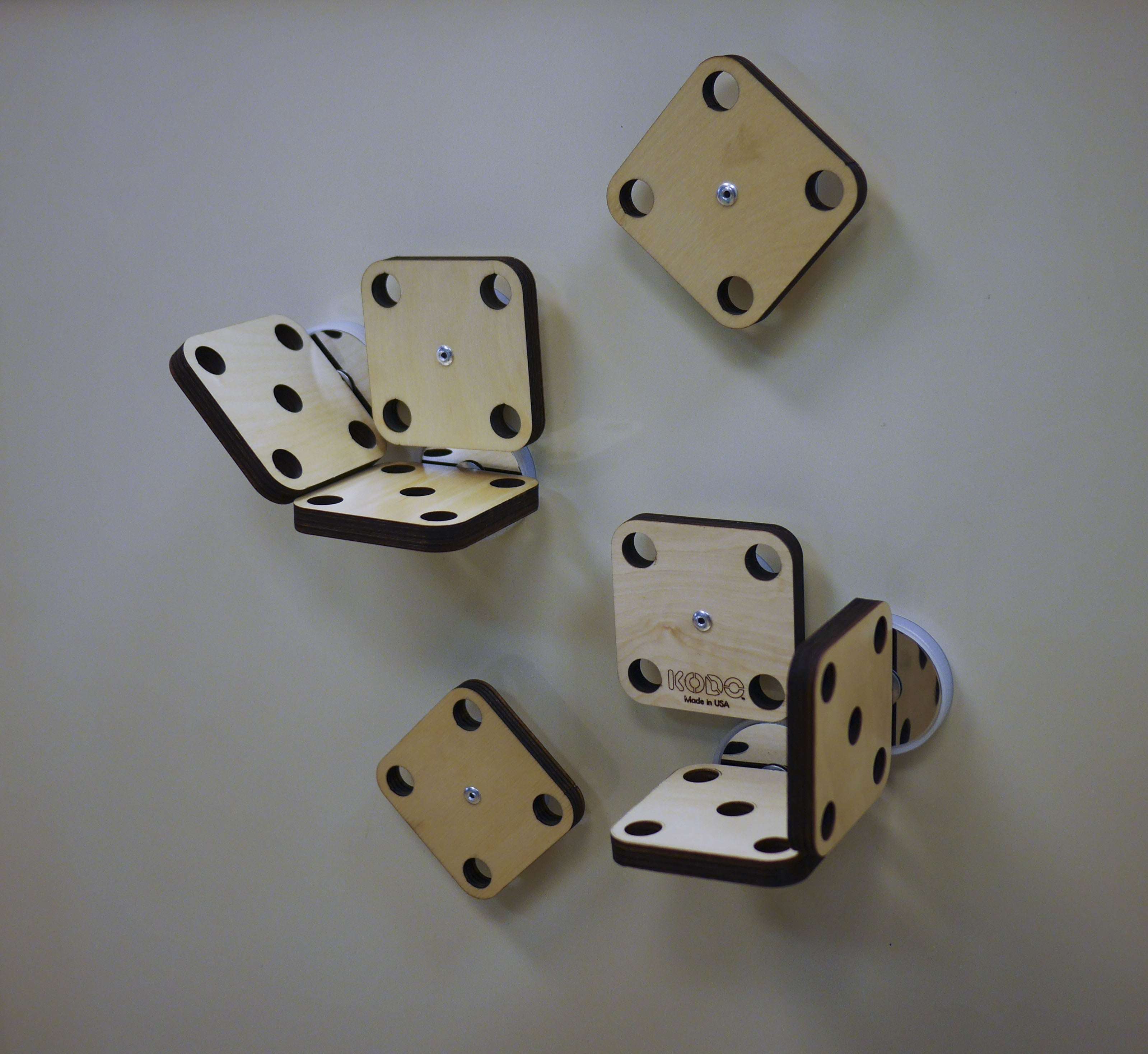 Light wood square magnetic mounting platforms with circular cutouts attached to a wall for engineering projects.