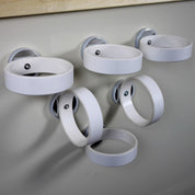Six white magnetic rings with silver bases attached to a wall for holding ramps and materials.