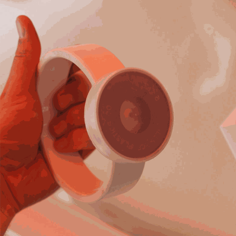 Hand holding a white plastic ring with a circular magnetic attachment for magnet wall play.