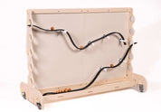Flexible black rubber ramp track attached to a light wood magnetic wall with rolling wooden balls.