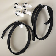 Flexible black rubber tracks and white magnetic pegs attached to a wall for a physics marble run.
