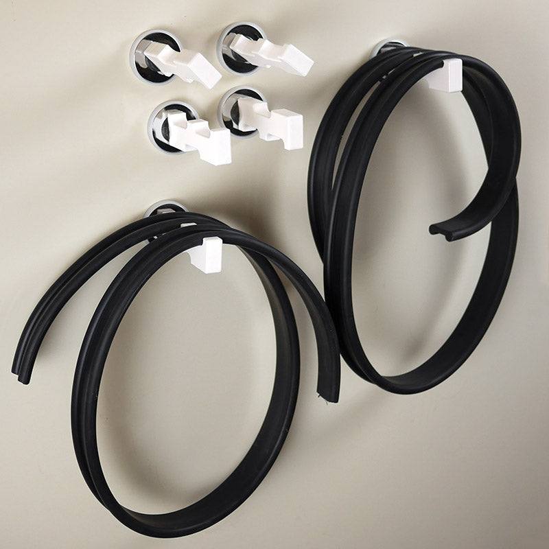 Flexible black rubber tracks and white magnetic pegs attached to a wall for a physics marble run.