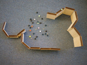 Wooden marble maze ramps arranged on a blue carpet with a collection of colorful glass marbles in the center.