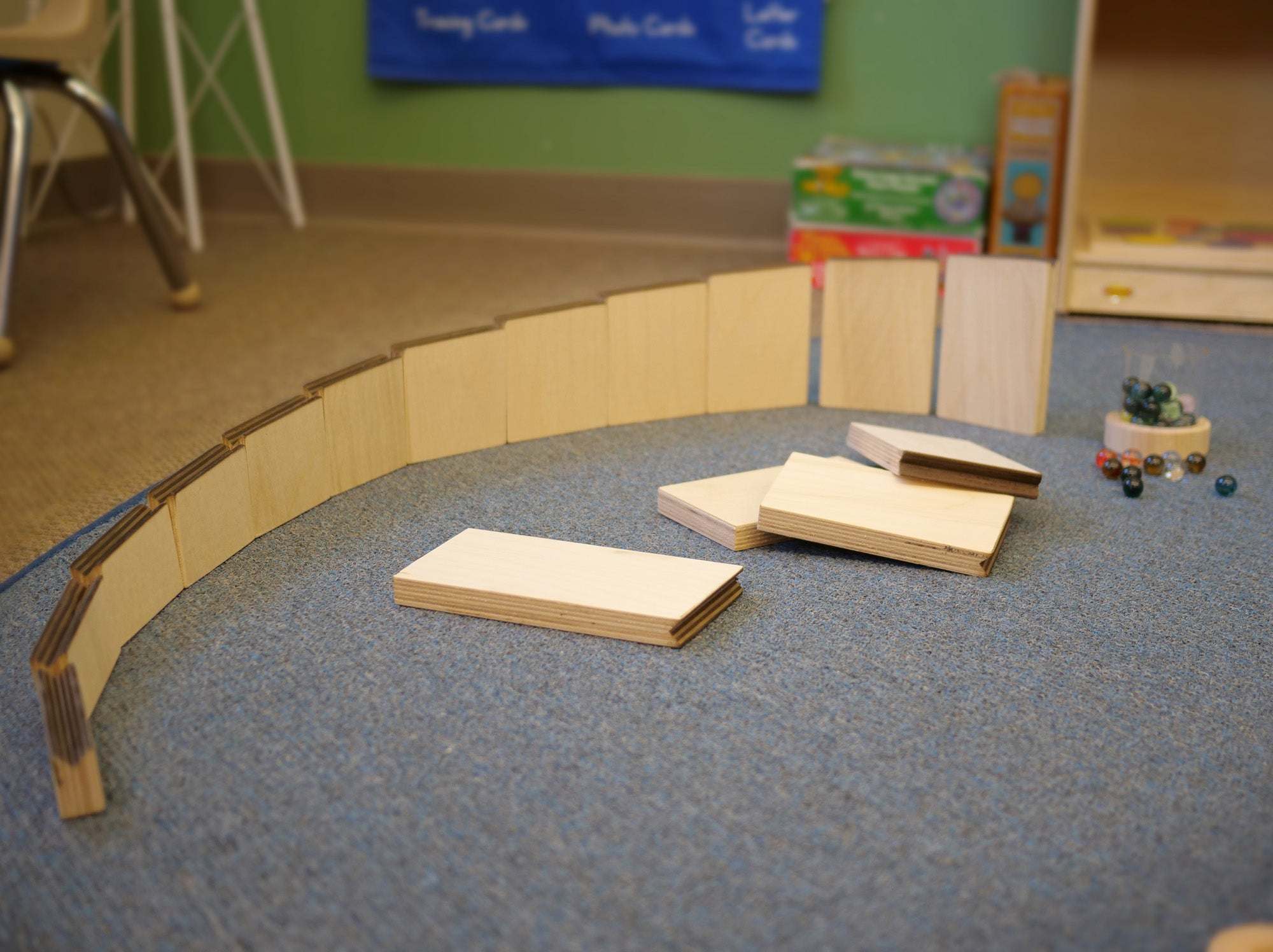 Curved wooden marble maze ramps arranged on a blue carpet with loose marbles nearby.