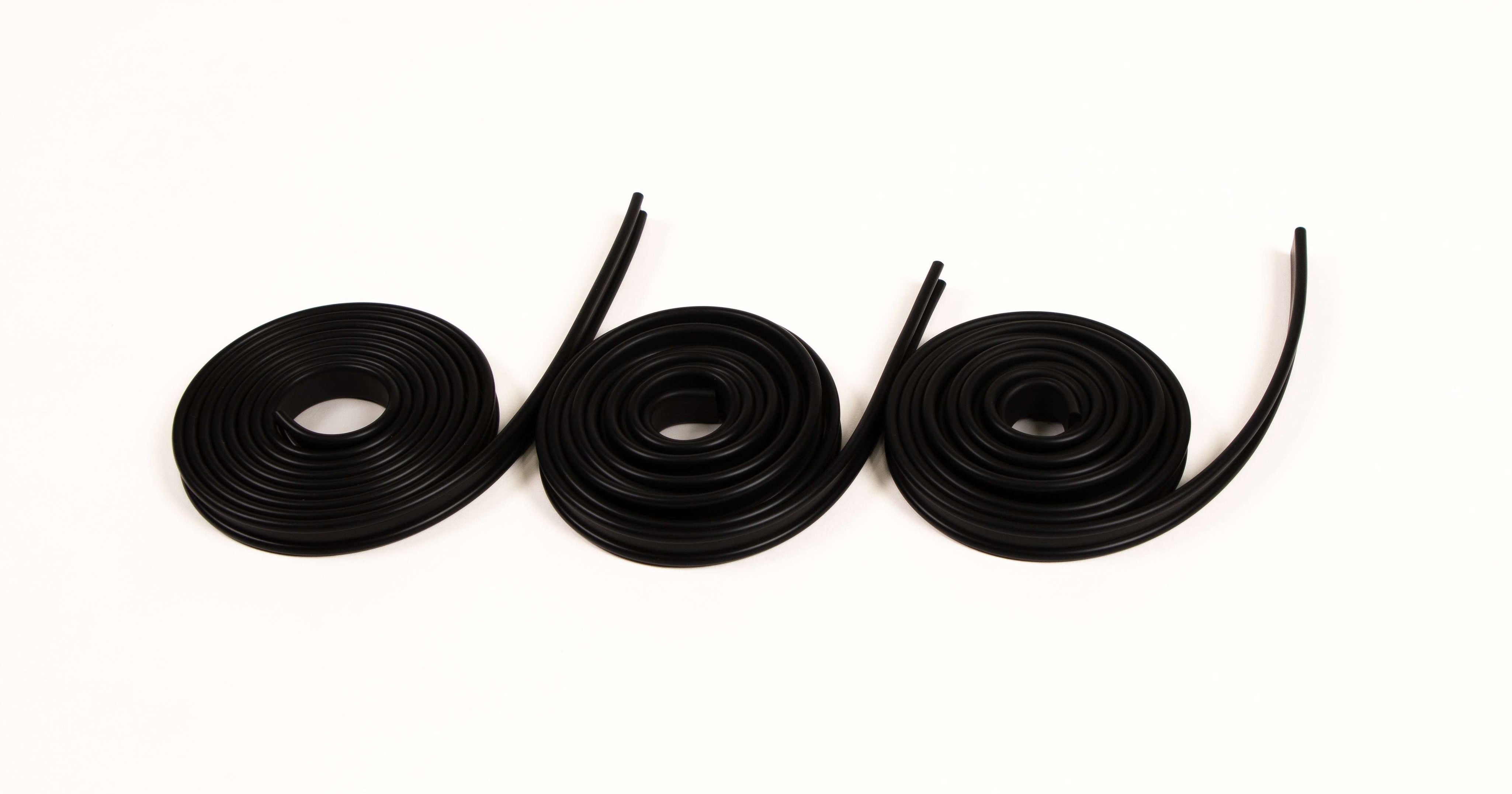 Three coils of flexible black rubber track for building STEM marble runs on a white background.