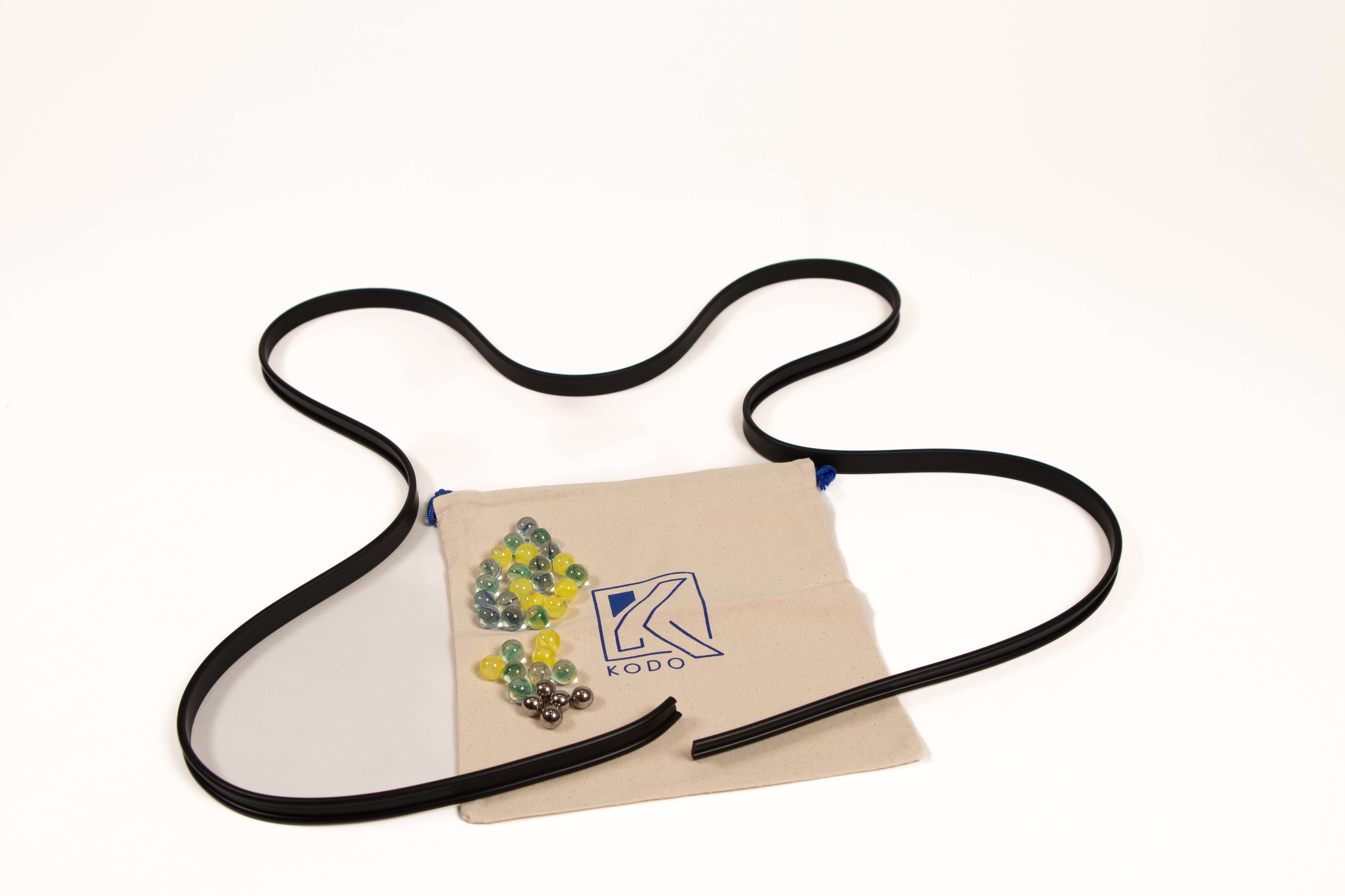 Flexible black rubber track for marble runs with a canvas storage bag, clear yellow marbles, and metal ball bearings.