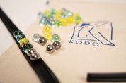 Black rubber marble ramp track with assorted glass and metal marbles on a Kodo branded canvas storage bag.