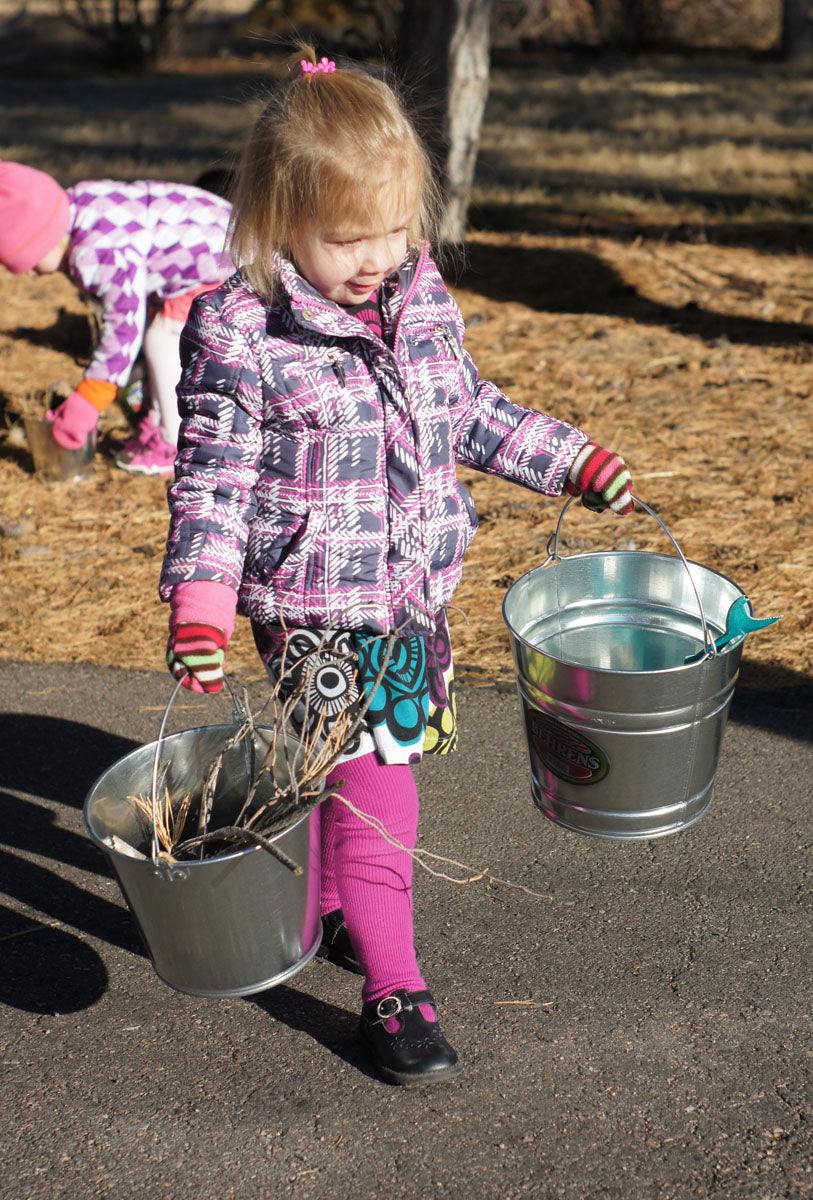 Child using metal pail outdoors for digging and learning activities
