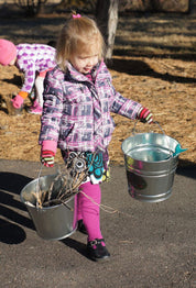 Child using metal pail outdoors for digging and learning activities