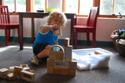 Child building with hardwood mirror blocks featuring Mylar mirrored centers and rounded corners on a carpeted floor.