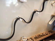 Black magnetic track mounted on a white wall with wooden balls for physics experiments.