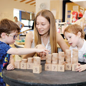 Teacher and children playing with a wooden Natural Number Stacker set featuring numbered beech wood blocks and discs.